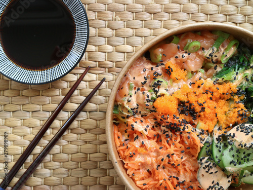 Salmon poke with chopsticks and a plate with soy sauce photo