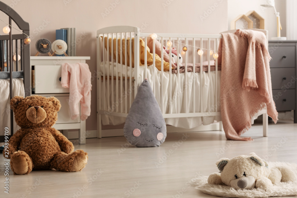 Cute plush toys and pink blankets in cozy bedroom interior for twin girls  with two cribs and bedside cabinets. Real photo Stock Photo