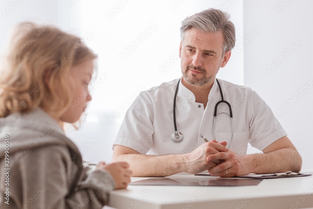 Helpful pediatrician and sick blond boy in a doctor's office Helpful pediatrician and sick blond boy in a doctor's office