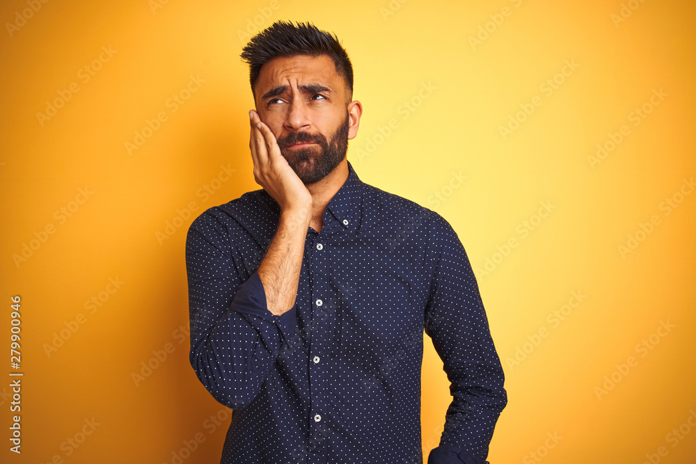 Young handsome indian businessman wearing shirt over isolated yellow background thinking looking tired and bored with depression problems with crossed arms. Young handsome indian businessman wearing shirt over isolated yellow background thinking looking tired and bored with depression problems with crossed arms.
