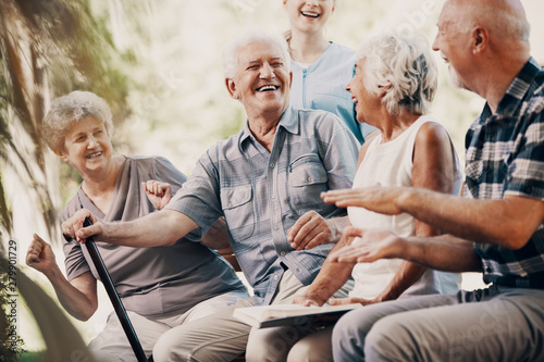 Happy elderly man with walking stick and smiling senior people relaxing in the garden photo