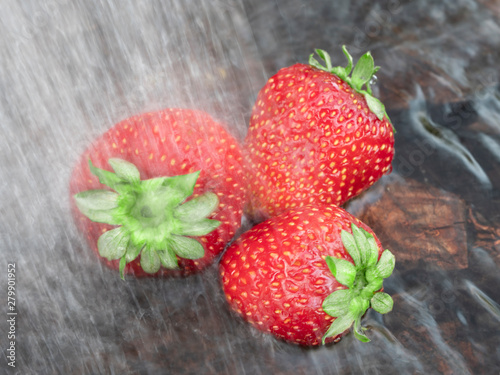 Strawberries under the shower. Three berries of ripe strawberries in water. Close-up. Still life.