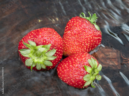 Strawberries in the water. Three berries ripe strawberries. Close-up. Still life.