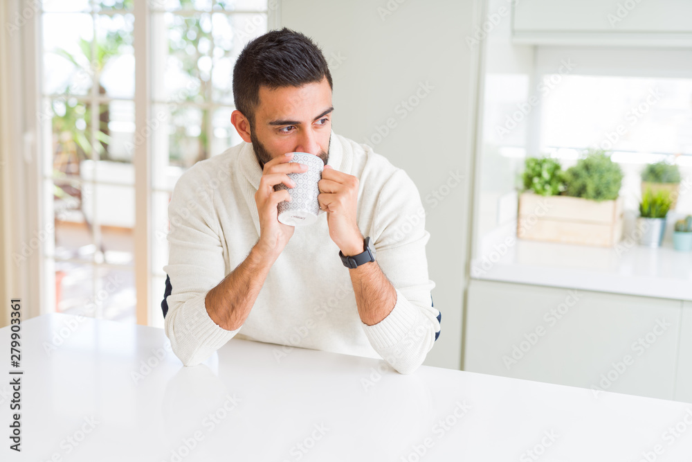 Handsome man smiling while enjoying drinking a cup of coffee in the morning Handsome man smiling while enjoying drinking a cup of coffee in the morning