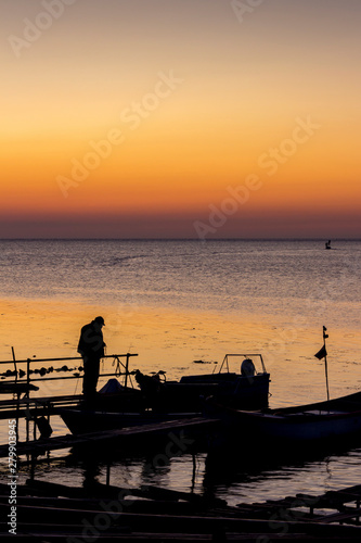 Silhouettes of fishermen and boats at the Port of Ahtopol, Black Sea Coast, Bulgaria at sunrise photo