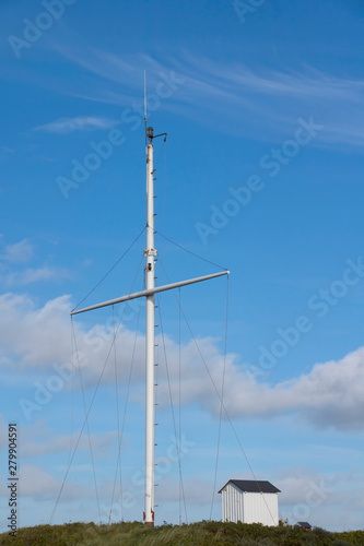 Mast and cottage on a dune at the North Sea coast with blue sky in Denmark