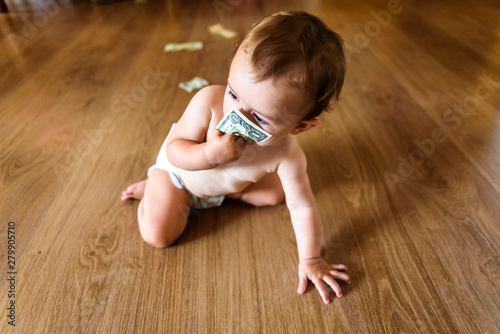 Baby happy to earn his own money, dollar bills that a father gives his son as a family to save them.