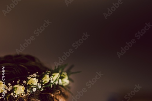 Diadem of white roses florets on the curved hair of a bride.
