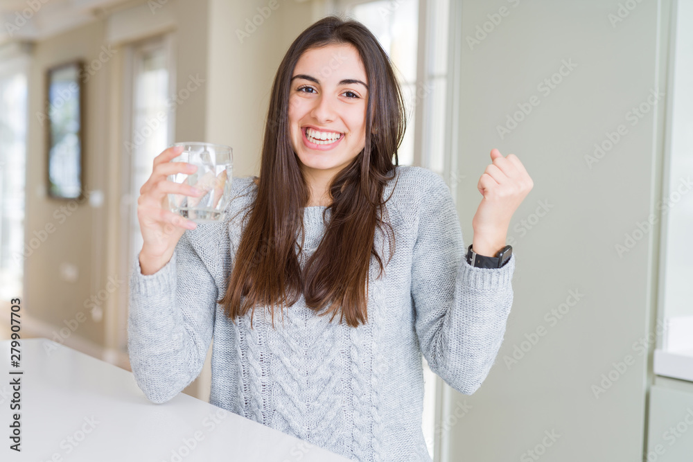 Beautiful young woman drinking a fresh glass of water screaming proud and celebrating victory and success very excited, cheering emotion Beautiful young woman drinking a fresh glass of water screaming proud and celebrating victory and success very excited, cheering emotion