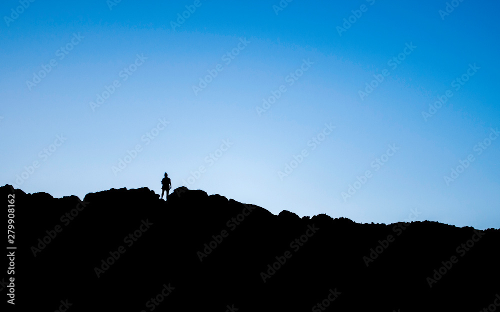 Silhouette of woman walking on edge of mountain