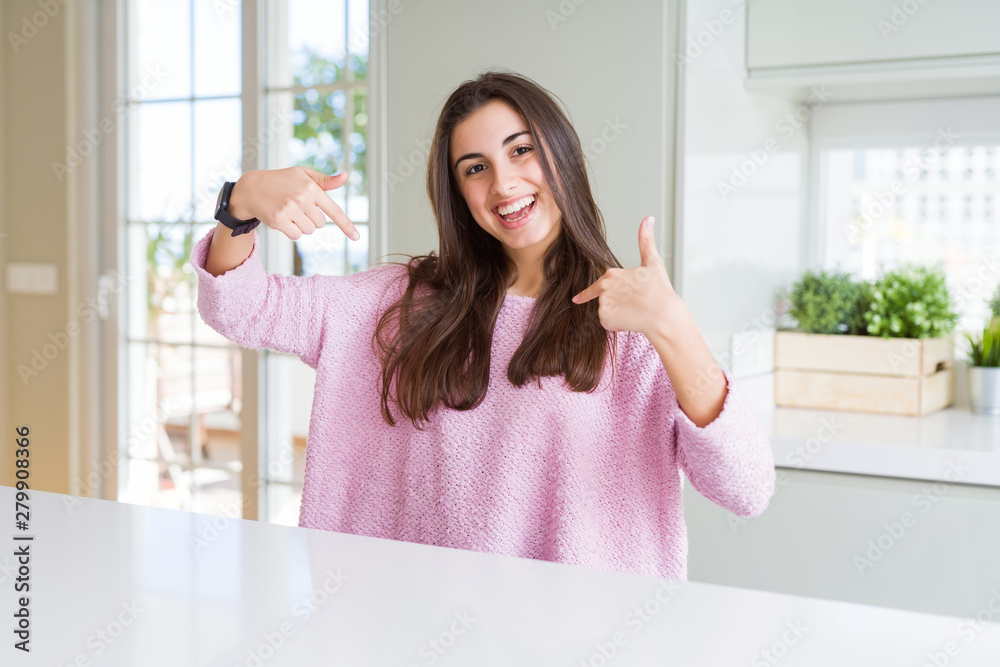 Beautiful young woman wearing pink sweater looking confident with smile on face, pointing oneself with fingers proud and happy.