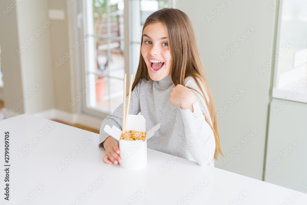 Beautiful young girl kid eating asian rice in delivery box with surprise face pointing finger to himself Beautiful young girl kid eating asian rice in delivery box with surprise face pointing finger to himself