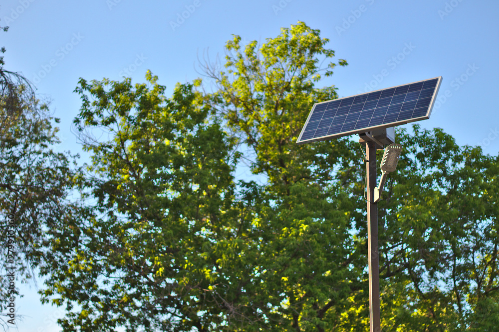 street lamp with a solar battery against a blue sky and trees street lamp with a solar battery against a blue sky and trees