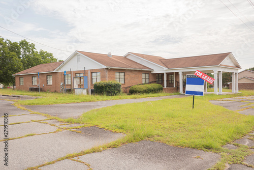 Canvas Print A rundown residential and commercial property in a suburban area with a for lease sign