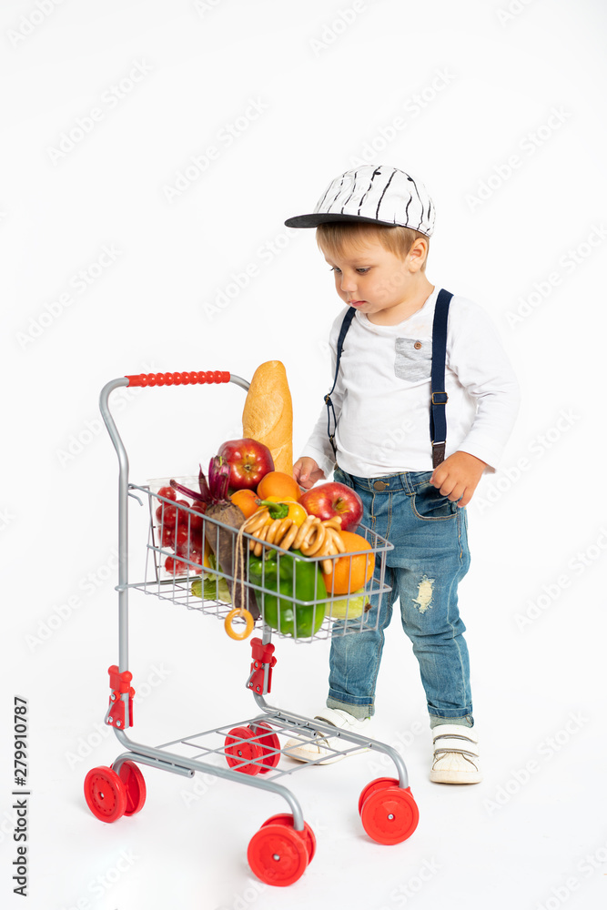cheerful little boy in casual clothes standing in studio with healthy food basket. Shopping, discount, sale concept cheerful little boy in casual clothes standing in studio with healthy food basket. Shopping, discount, sale concept