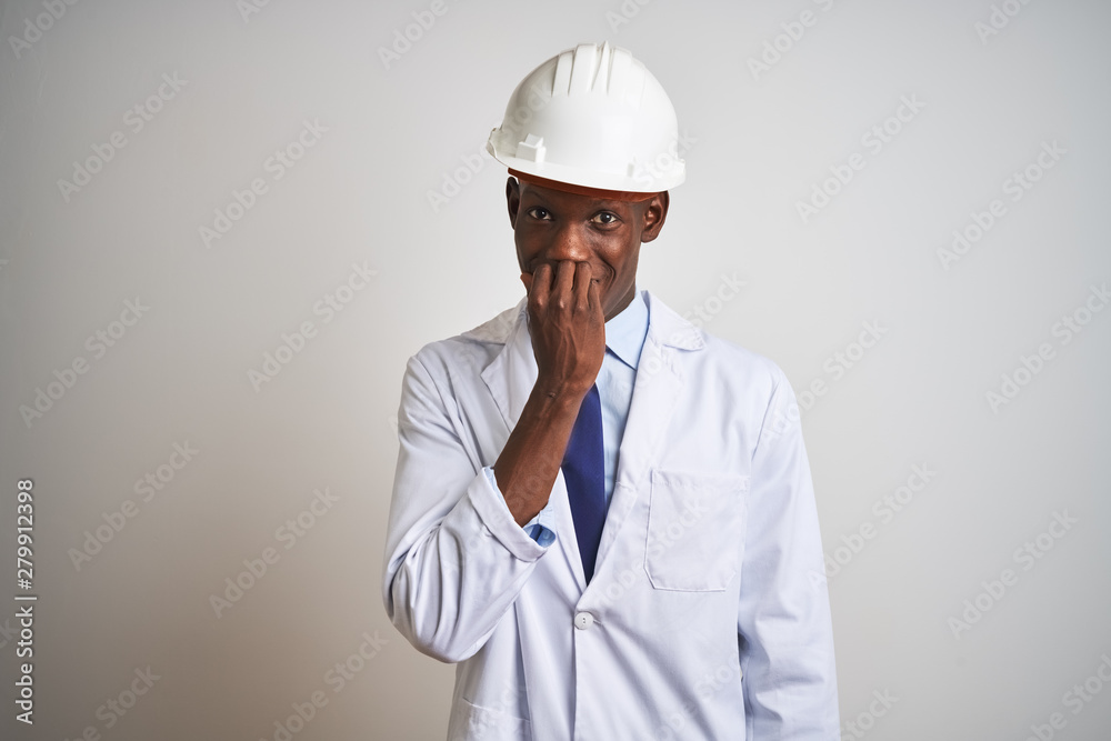 African american engineer man wearing coat and helmet over isolated white background looking stressed and nervous with hands on mouth biting nails. Anxiety problem. African american engineer man wearing coat and helmet over isolated white background looking stressed and nervous with hands on mouth biting nails. Anxiety problem.