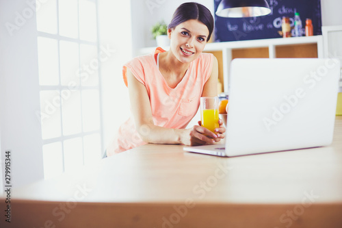Young woman in kitchen with laptop computer looking recipes, smiling. Food blogger concept © lenets_tan