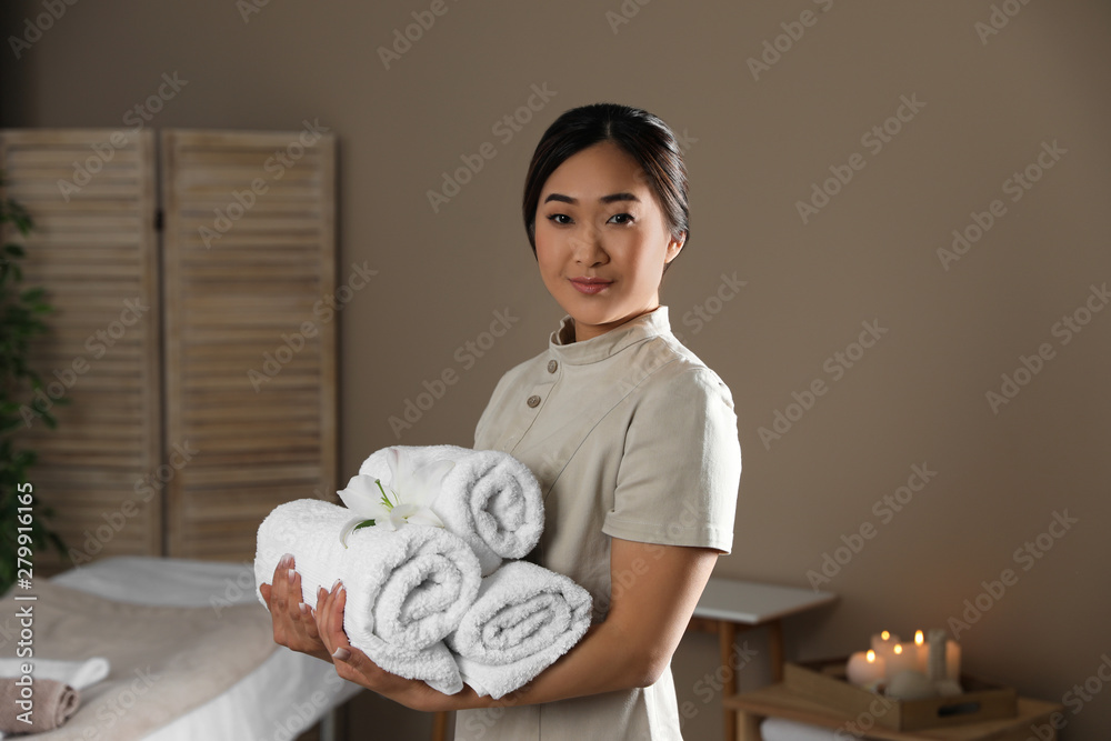 Portrait of young Asian masseur with towels in spa salon Portrait of young Asian masseur with towels in spa salon