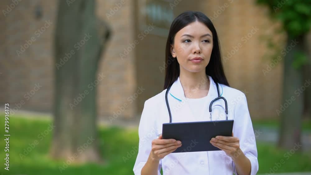 Female nurse checking examination results at tablet pc, hospital park, health Female nurse checking examination results at tablet pc, hospital park, health