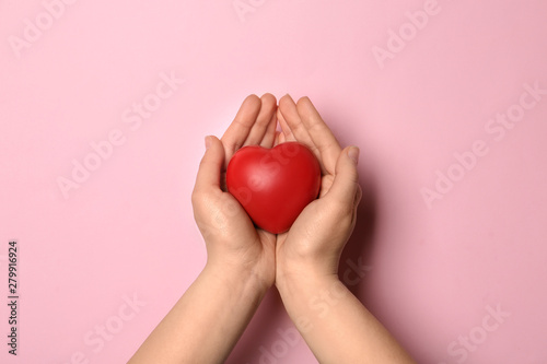 Fototapeta Naklejka Na Ścianę i Meble -  Woman holding decorative heart on pink background, top view