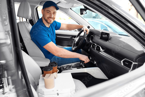 Male courier with orders in car. Food delivery service
