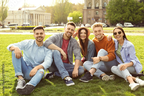 Happy people sitting on green grass in park