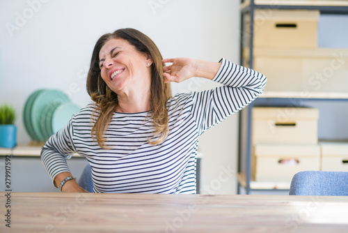 Middle age senior woman sitting at the table at home stretching back  tired and relaxed  sleepy and yawning for early morning
