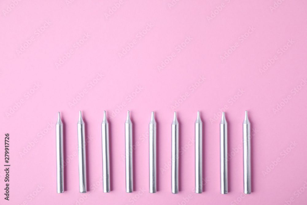 Silver birthday candles on pink background, top view with space for text Silver birthday candles on pink background, top view with space for text