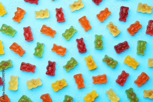 Фотография Delicious bright jelly bears on blue background, flat lay