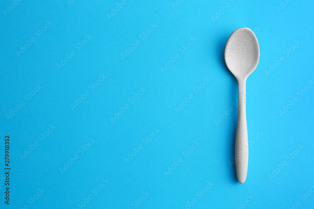 Clean empty spoon on blue background, top view. Space for text Clean empty spoon on blue background, top view. Space for text