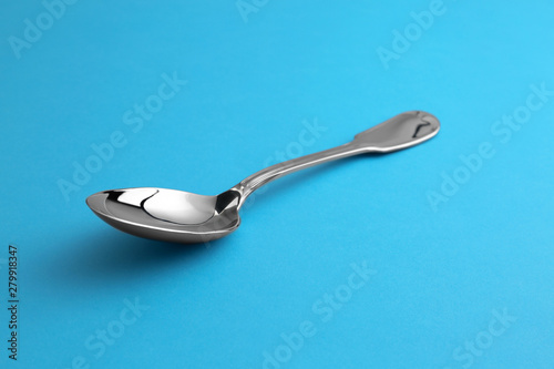 Clean empty tea spoon on blue background