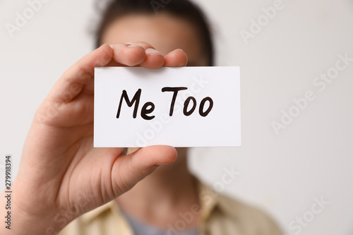 Woman holding paper with text MeToo against light background, closeup. Stop sexual assault