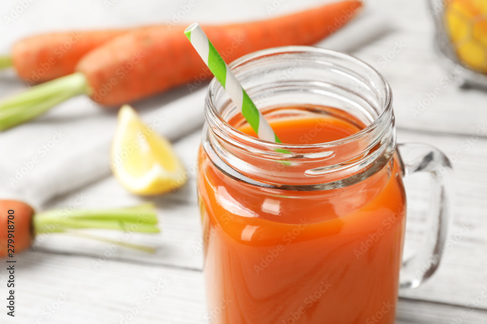 Mason jar with fresh carrot juice on white wooden table, space for text Mason jar with fresh carrot juice on white wooden table, space for text