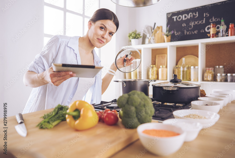 Young woman standing by the stove in the kitchen Young woman standing by the stove in the kitchen