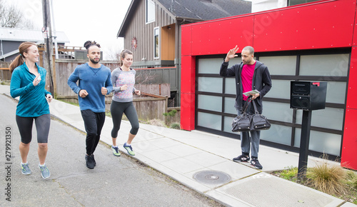 group of people jogging past home where neighbor waves photo