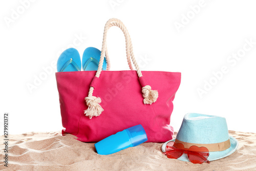 Stylish coral bag and beach accessories on sand against white background