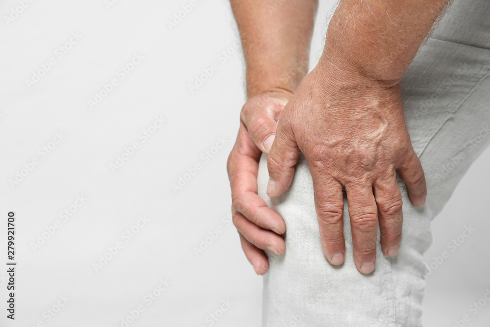Fototapeta premium Senior man having knee problems on grey background, closeup. Space for text
