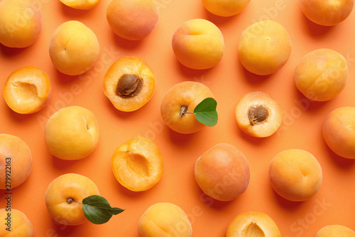 Fotografia Delicious ripe sweet apricots on orange background, flat lay