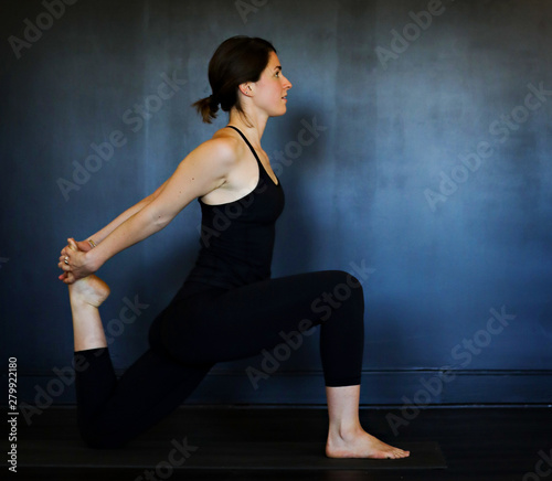 Young white woman does yoga poses in a studio. 
