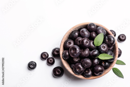 Bowl of fresh acai berries with leaves on white background, top view photo