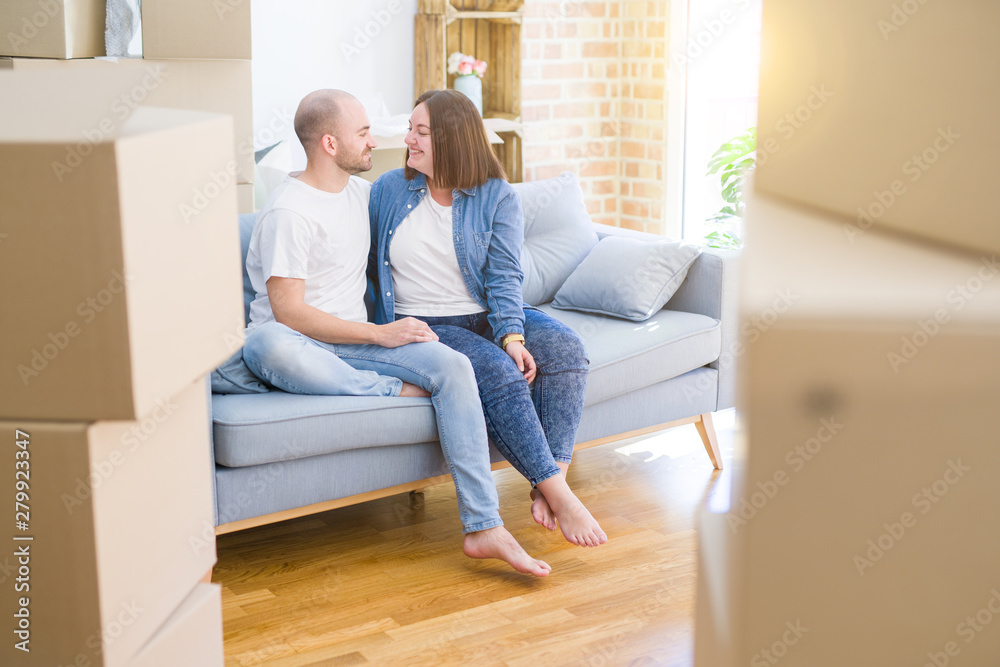 Young couple in love relaxing and hugging sitting on the sofa at new home, smiling very happy for moving to a new apartment Young couple in love relaxing and hugging sitting on the sofa at new home, smiling very happy for moving to a new apartment