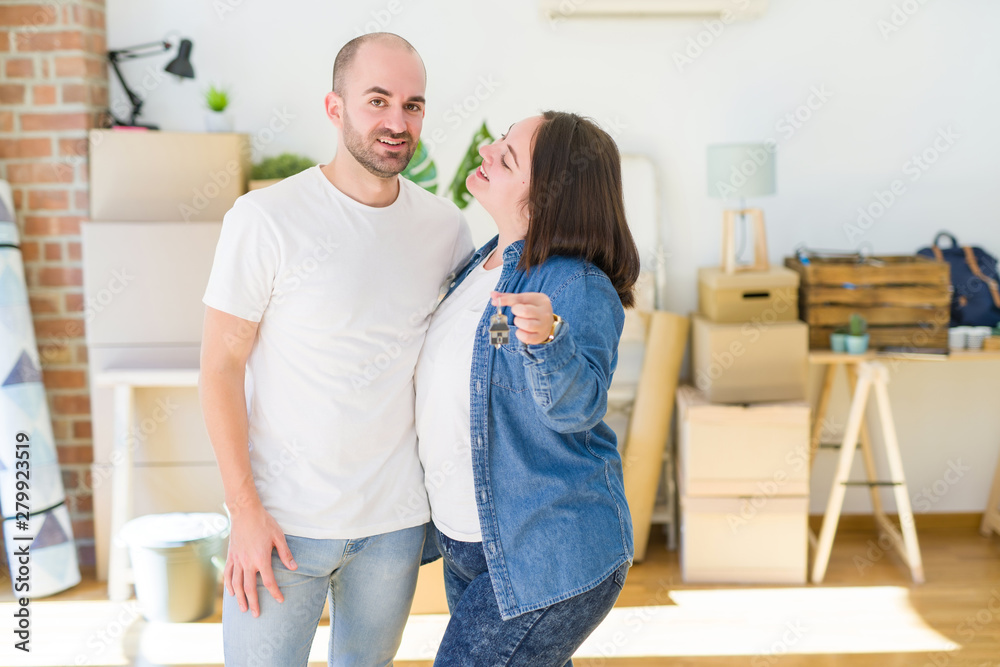 Young couple smiling very happy showing keys of new home, moving and buying new apartmet concept Young couple smiling very happy showing keys of new home, moving and buying new apartmet concept