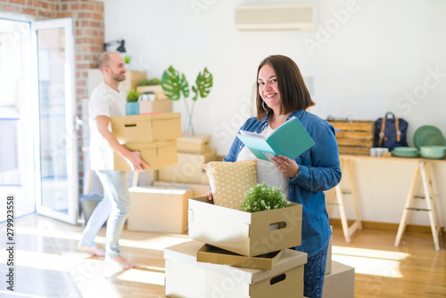 Young couple moving to new apartment, beautiful woman moving cardboard boxes and smiling happy © Krakenimages.com