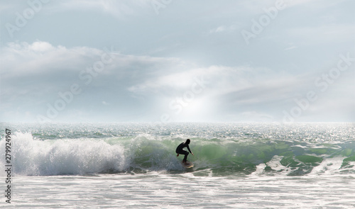 Surfer in black wetsuit on green ocean wave