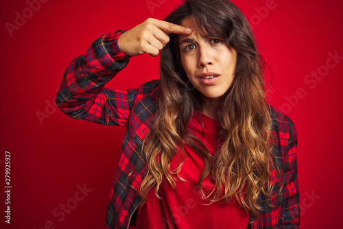Young beautiful woman wearing casual jacket standing over red isolated background hand on mouth telling secret rumor, whispering malicious talk conversation