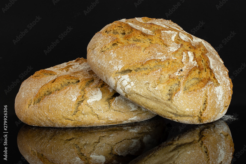 Group of two whole fresh baked rye wheat bread isolated on black glass