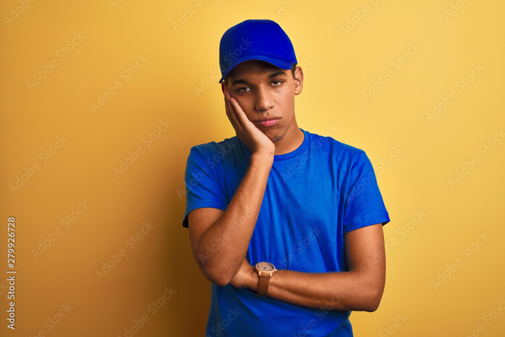 Young handsome arab delivery man standing over isolated yellow background thinking looking tired and bored with depression problems with crossed arms. Young handsome arab delivery man standing over isolated yellow background thinking looking tired and bored with depression problems with crossed arms.
