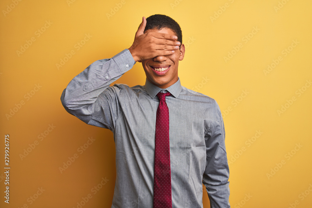 Young handsome arab businessman wearing shirt and tie over isolated yellow background smiling and laughing with hand on face covering eyes for surprise. Blind concept. Young handsome arab businessman wearing shirt and tie over isolated yellow background smiling and laughing with hand on face covering eyes for surprise. Blind concept.