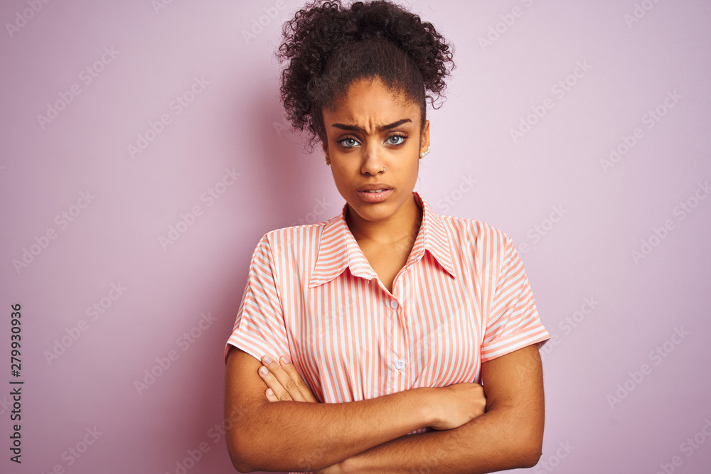 Obraz premium African american woman wearing casual striped shirt standing over isolated pink background skeptic and nervous, disapproving expression on face with crossed arms. Negative person.