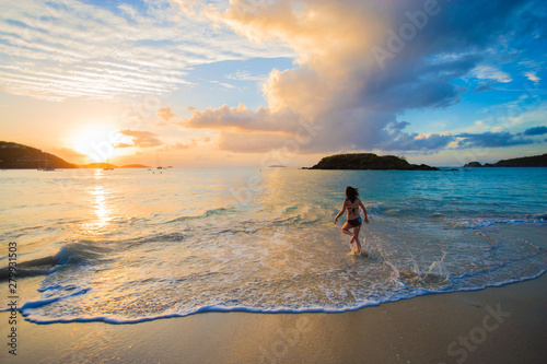 Beautiful girl wearing a bikini walking out of the ocean at sunset in Cinnamon Bay, St. John, USVI photo